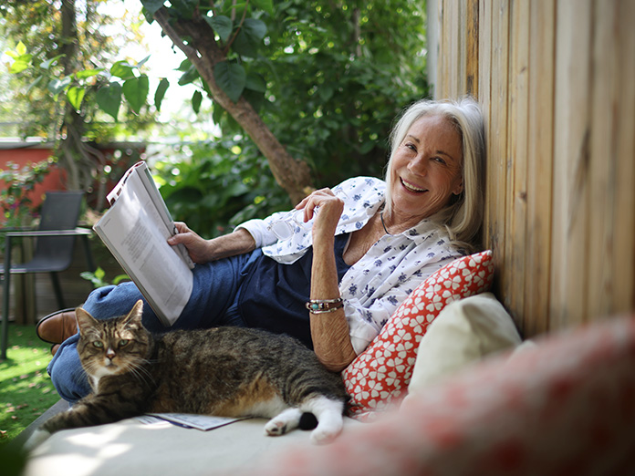 Older woman relaxes and reads newspaper on park bench