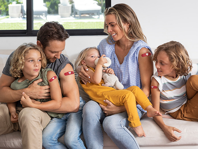 Familia sentada mostrando vacunas contra la influenza
