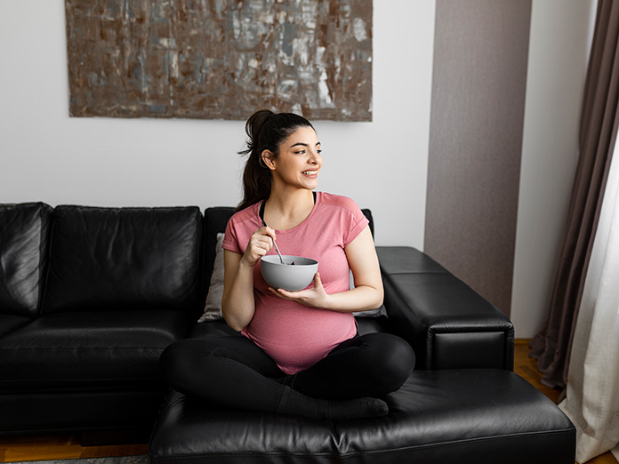 little girl holds her ear up next to her mum's pregnant belly