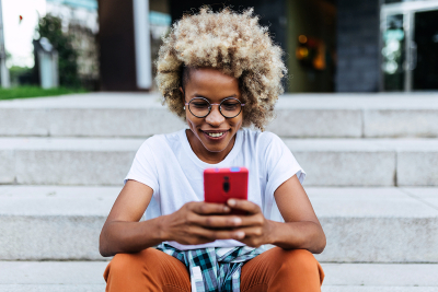 A woman on her phone sitting on stairs outside